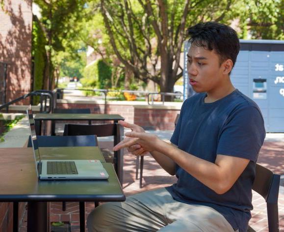 Student on campus using his laptop for a video call.